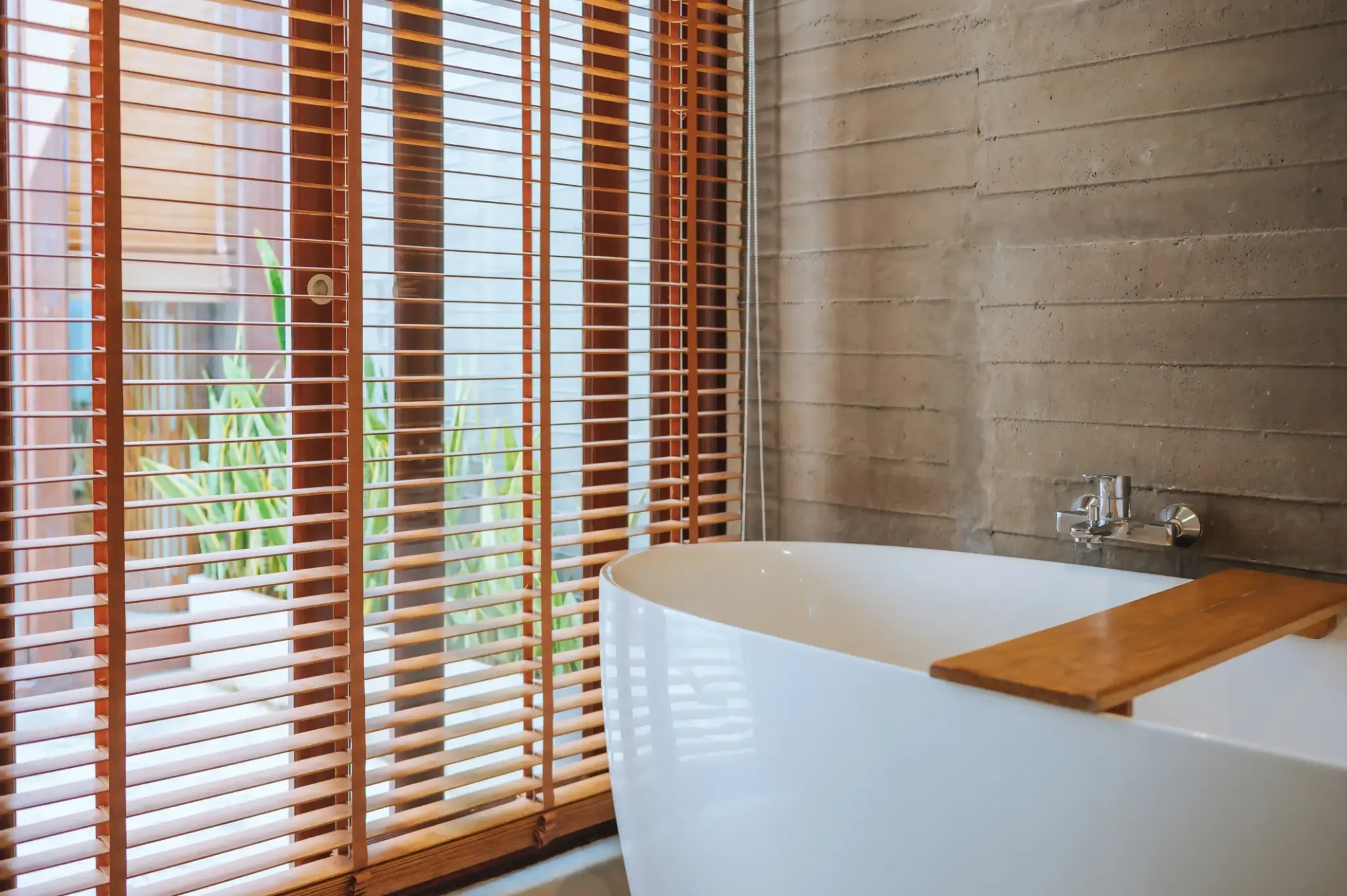 Naturalna łazienka z bambusowymi  żaluzjami i betonową ścianą – ciepły klimat w nowoczesnym wnętrzu.